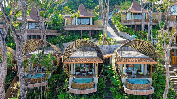Un complexe hôtelier comprenant plusieurs bungalows, chacun doté d’une structure circulaire en bois et d’une piscine, le tout entouré d’une végétation luxuriante.