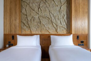 Een hotelkamer met twee bedden, houten hoofdeinden en een gestructureerde wanddecoratie.