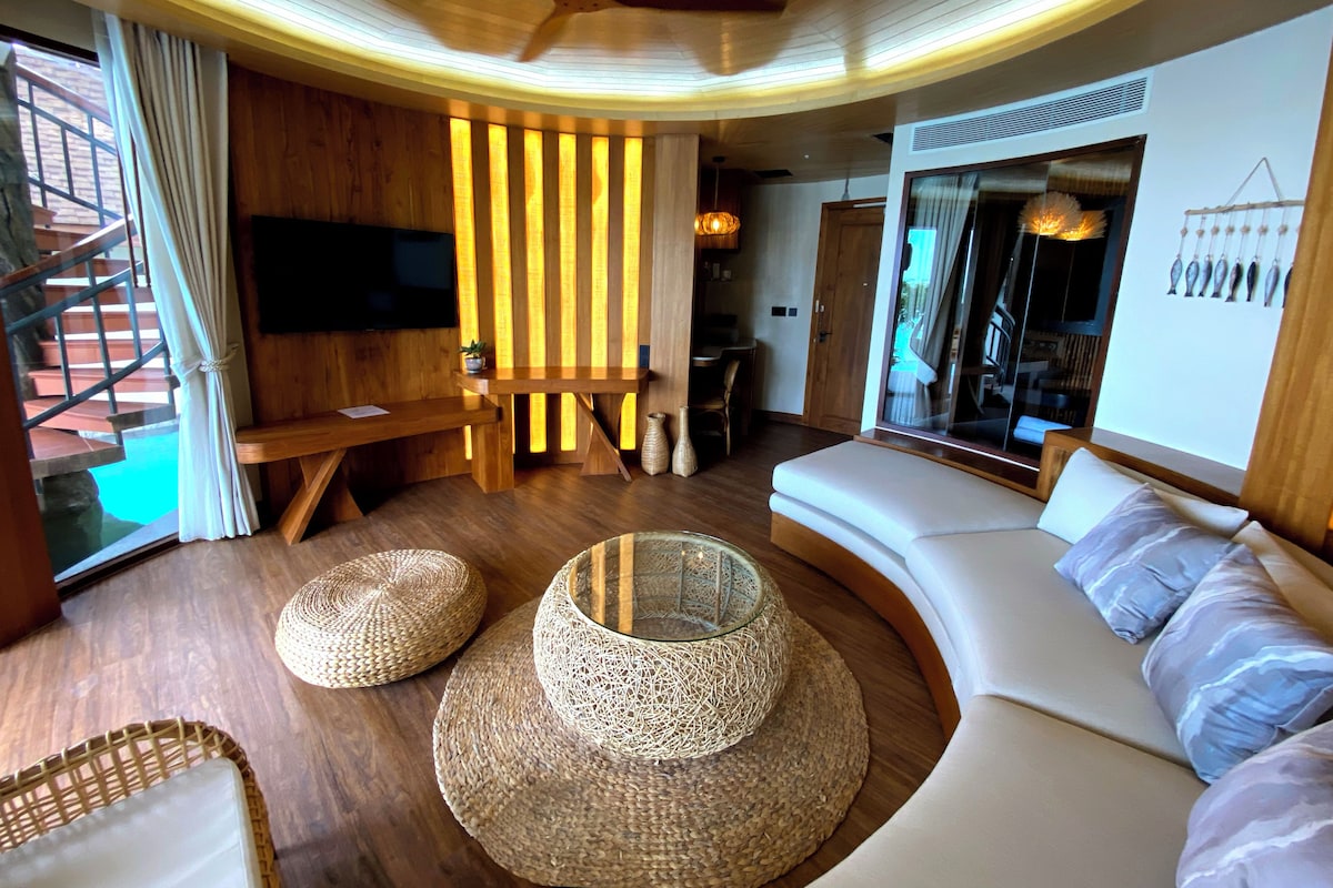Een moderne woonkamer met een gebogen bank, een flatscreen televisie, houten details en een trap.