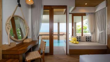 Une pièce avec un bureau en bois, une chaise, un lit, un grand miroir et une vue sur la mer.