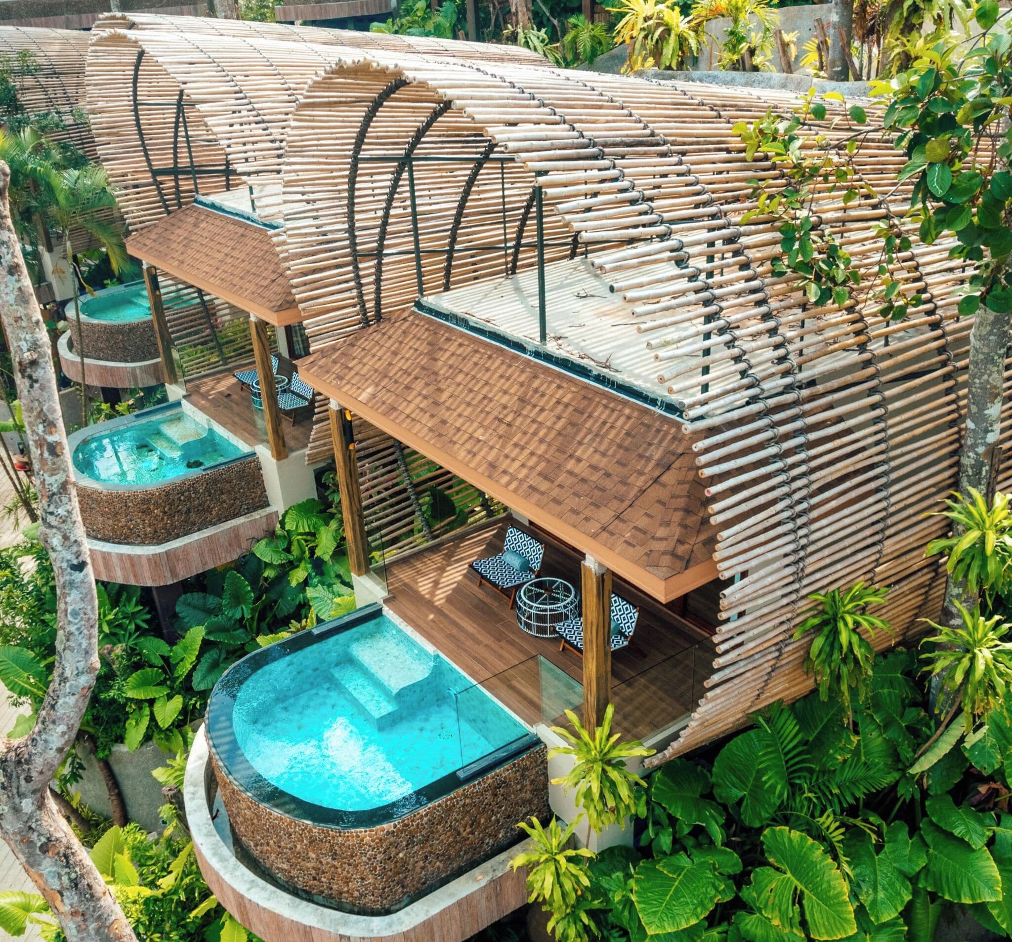 A modern, multi-level building with a bamboo exterior, featuring a pool on each level and outdoor seating areas.