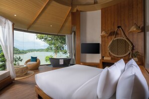 Een moderne slaapkamer met een groot bed, een flatscreen televisie, een houten plafond en uitzicht op een meer.