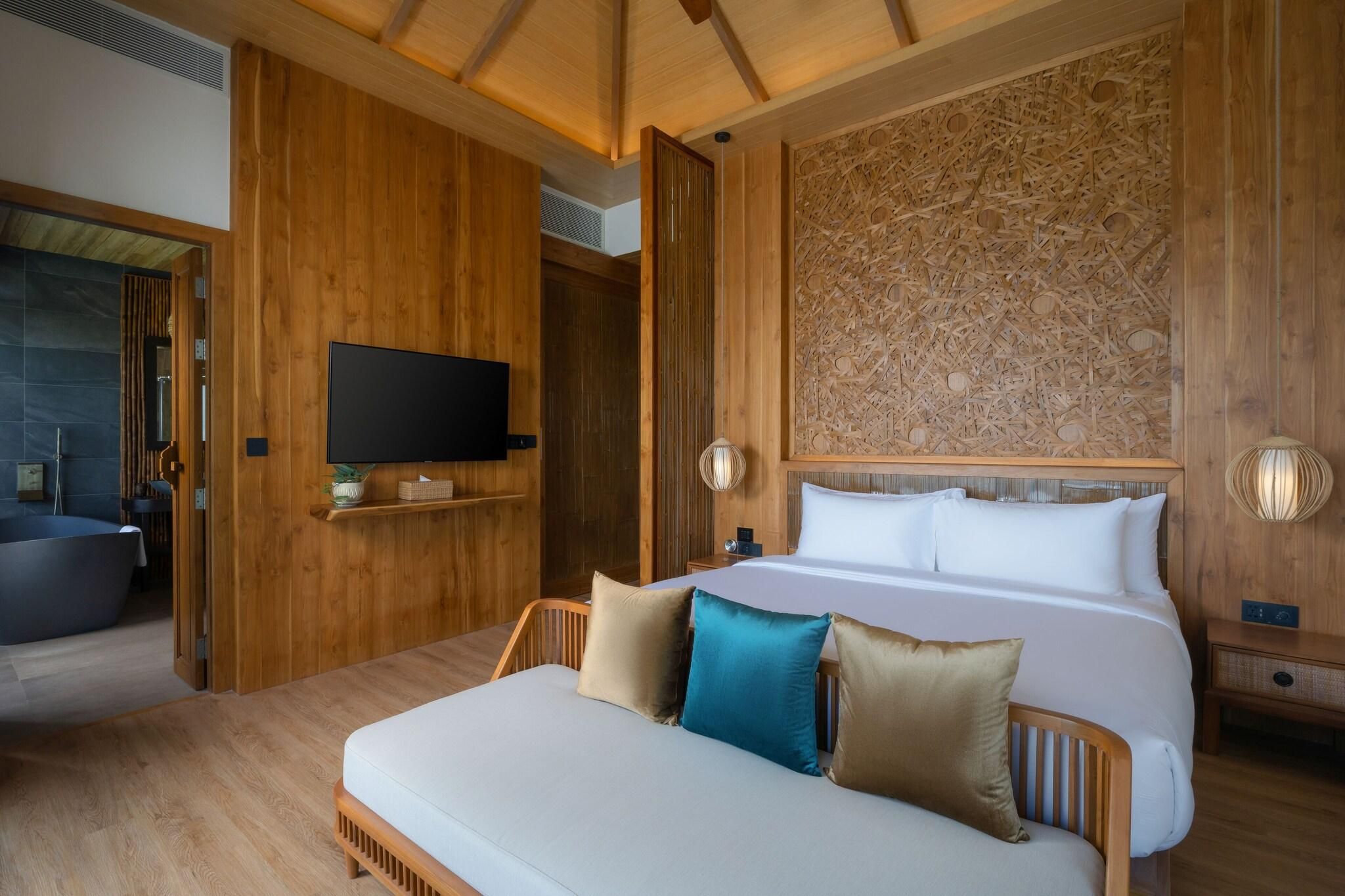 Une chambre à coucher aux murs lambrissés, avec un lit, une table de chevet et un téléviseur.