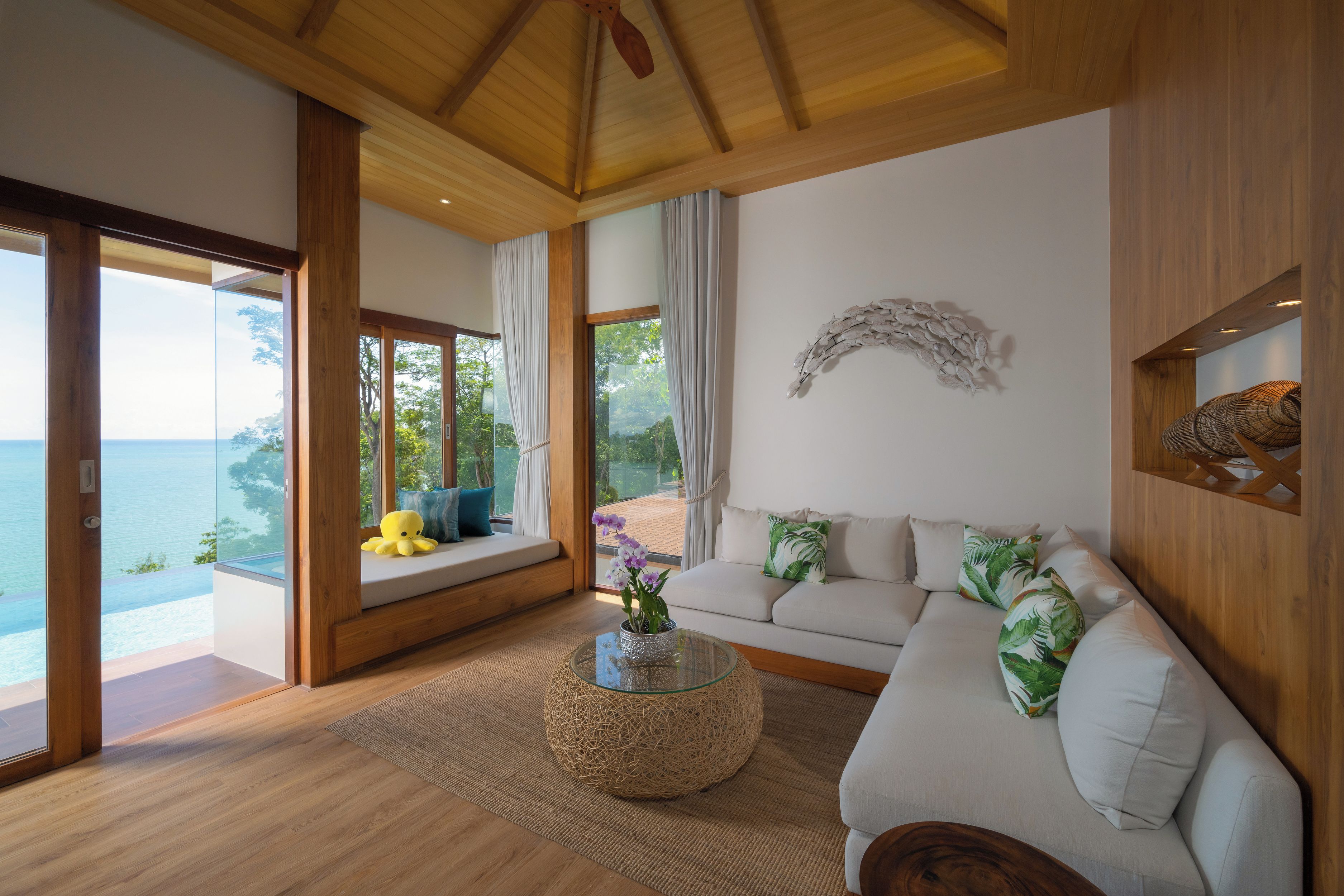 A modern living room with a sofa, a round coffee table, and a view of the sea.