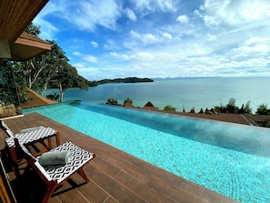 An infinity pool with a view of a large body of water and distant land. - Sinae Phuket Luxury Hotel (Ratsada)