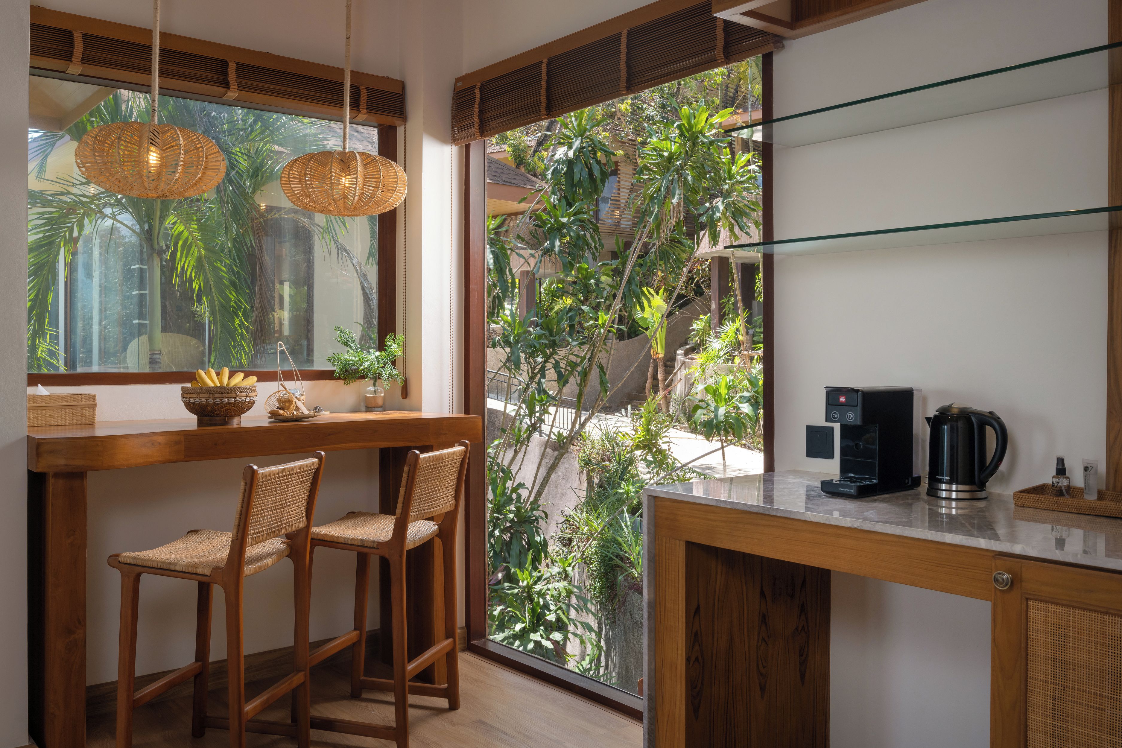 Una cocina con cafetera, una cesta y una ventana con vistas al verdor.