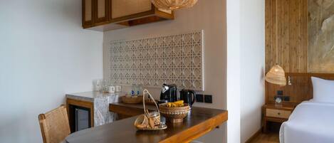 Una habitación compacta con una mesa de madera, una cama blanca y una zona de kitchenette.