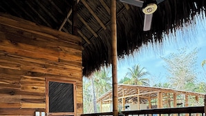 A wooden cabin with a thatched roof, a wooden deck, and two chairs. - RINCON DEL MANGLE (San Onofre)