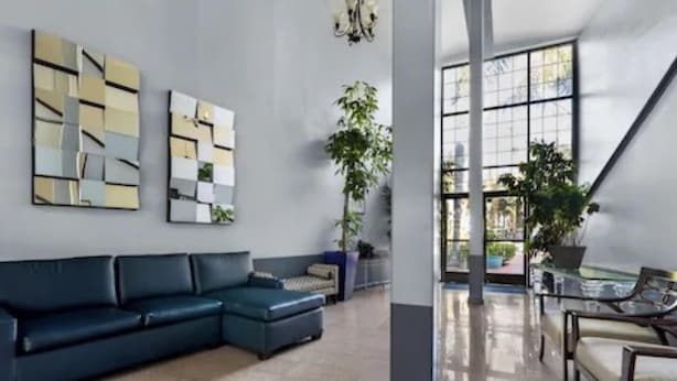 A modern living room with a sectional sofa, a glass coffee table, and abstract wall art.