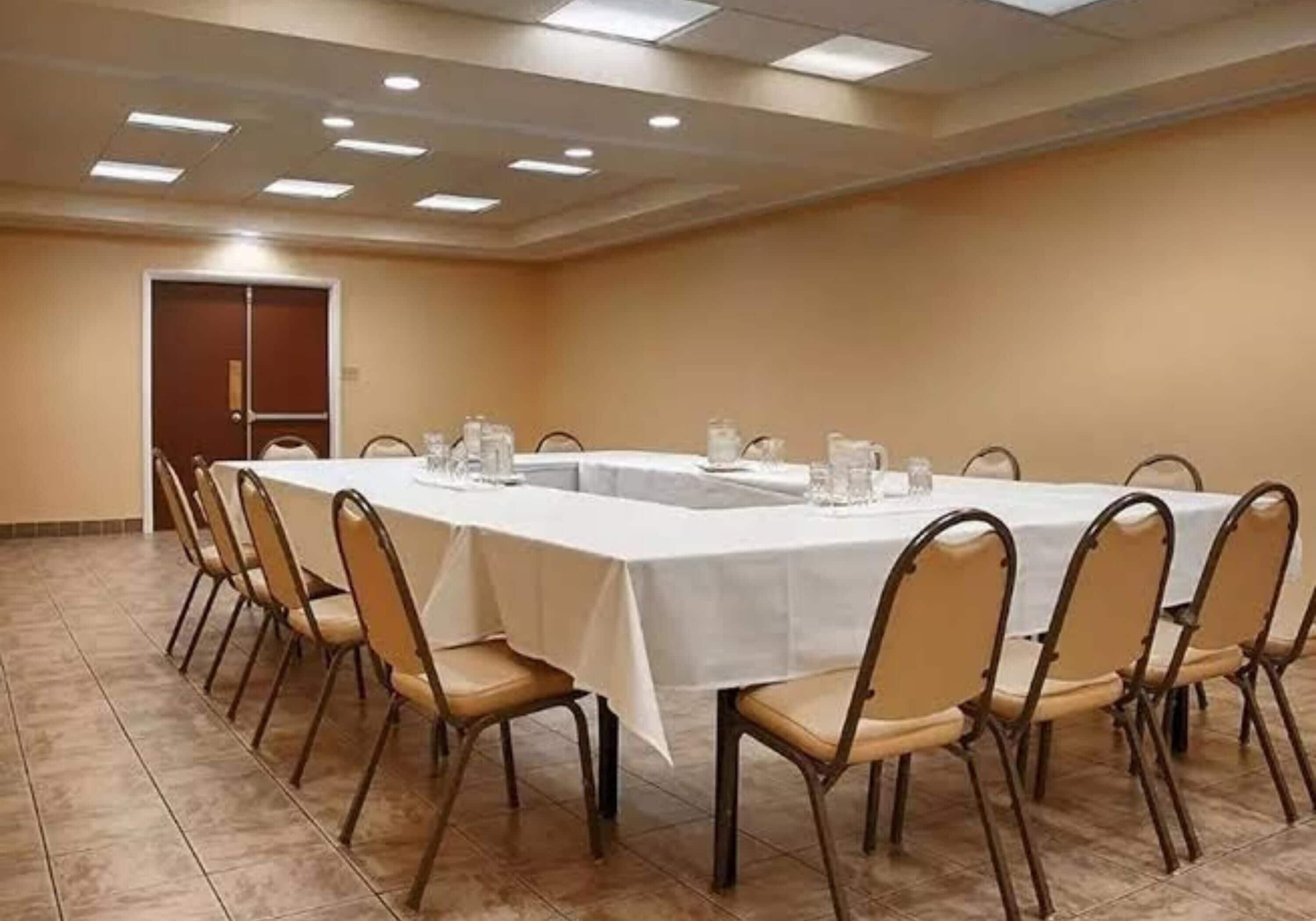 Una sala de conferències amb una taula llarga, cadires i una porta.
