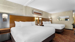 A hotel room with two beds, a wooden headboard, bedside lamps, a phone, and a mirror.