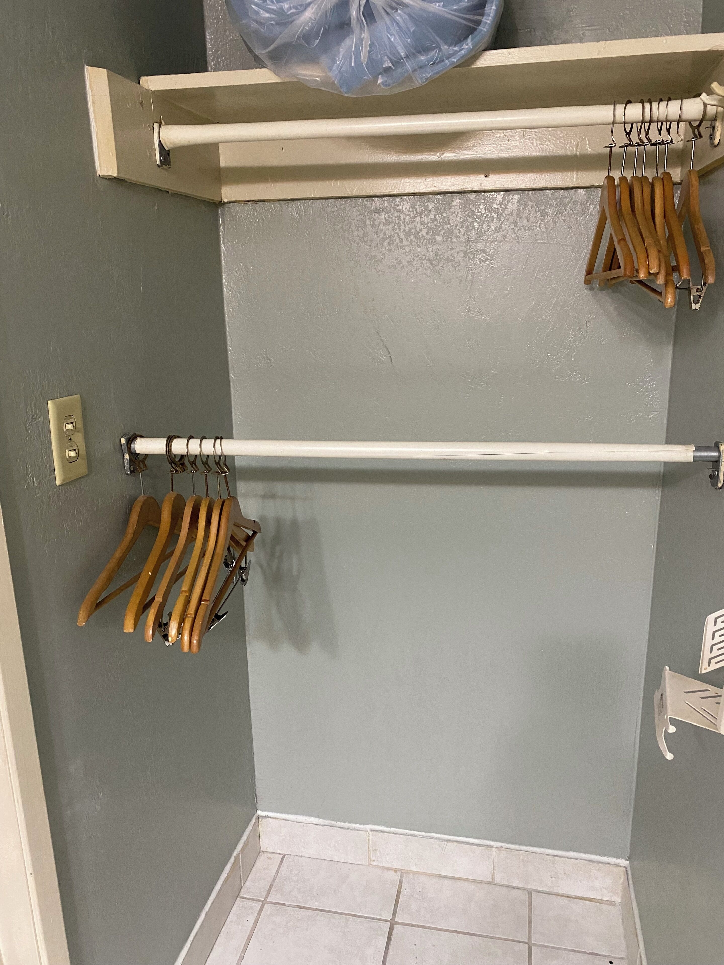 A corner of a room with a grey wall, a white towel bar, and wooden hangers.
