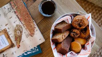 A table with a basket of muffins and a cup of coffee, a framed map, and a book titled "GOVERNORS ISLAND".