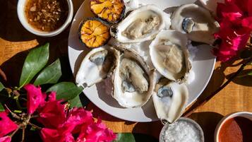 Een bord oesters met ingelegde uien en een klein schaaltje saus.