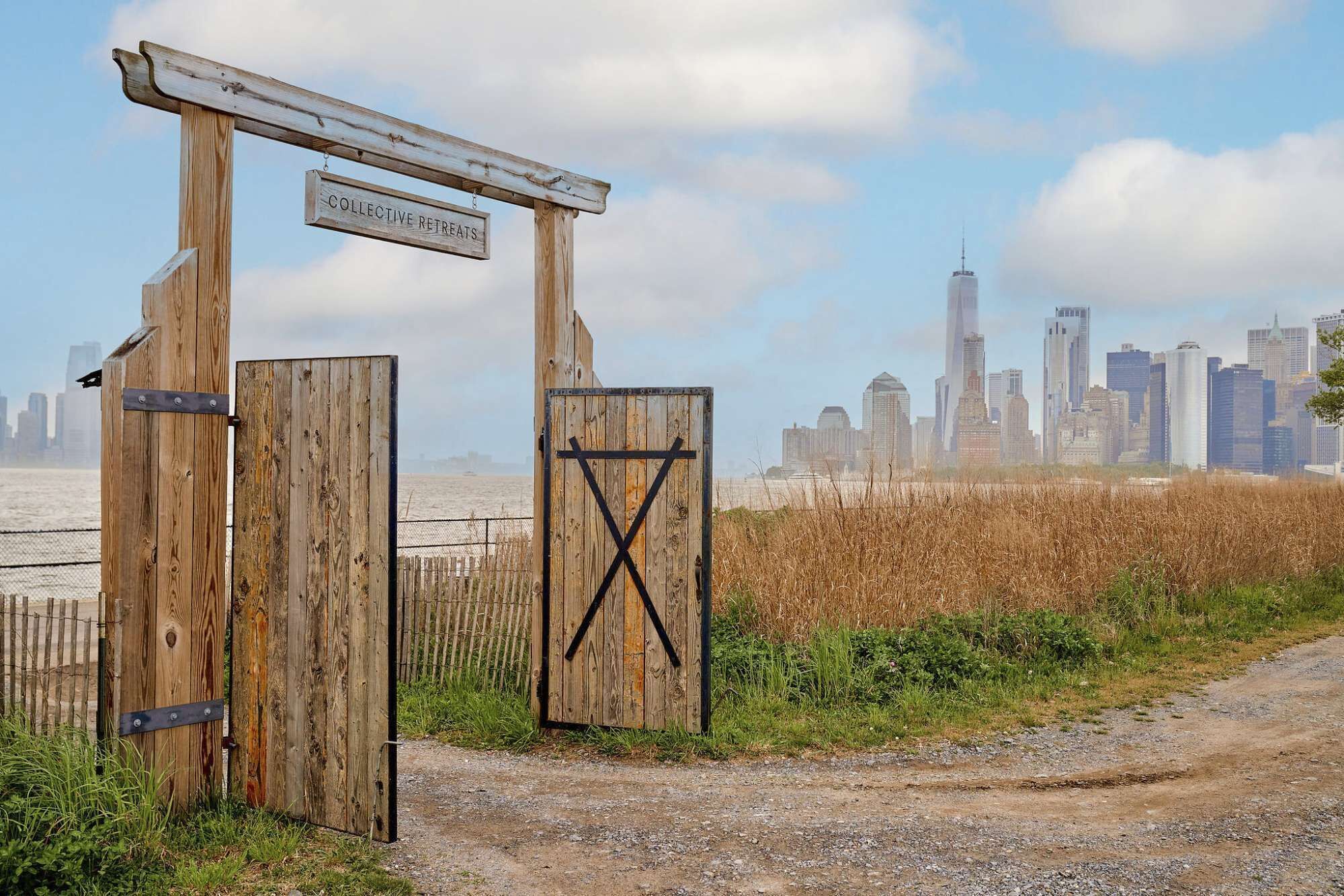A wooden gate with a sign reading 'Collective Retreats' and a city skyline in the background.