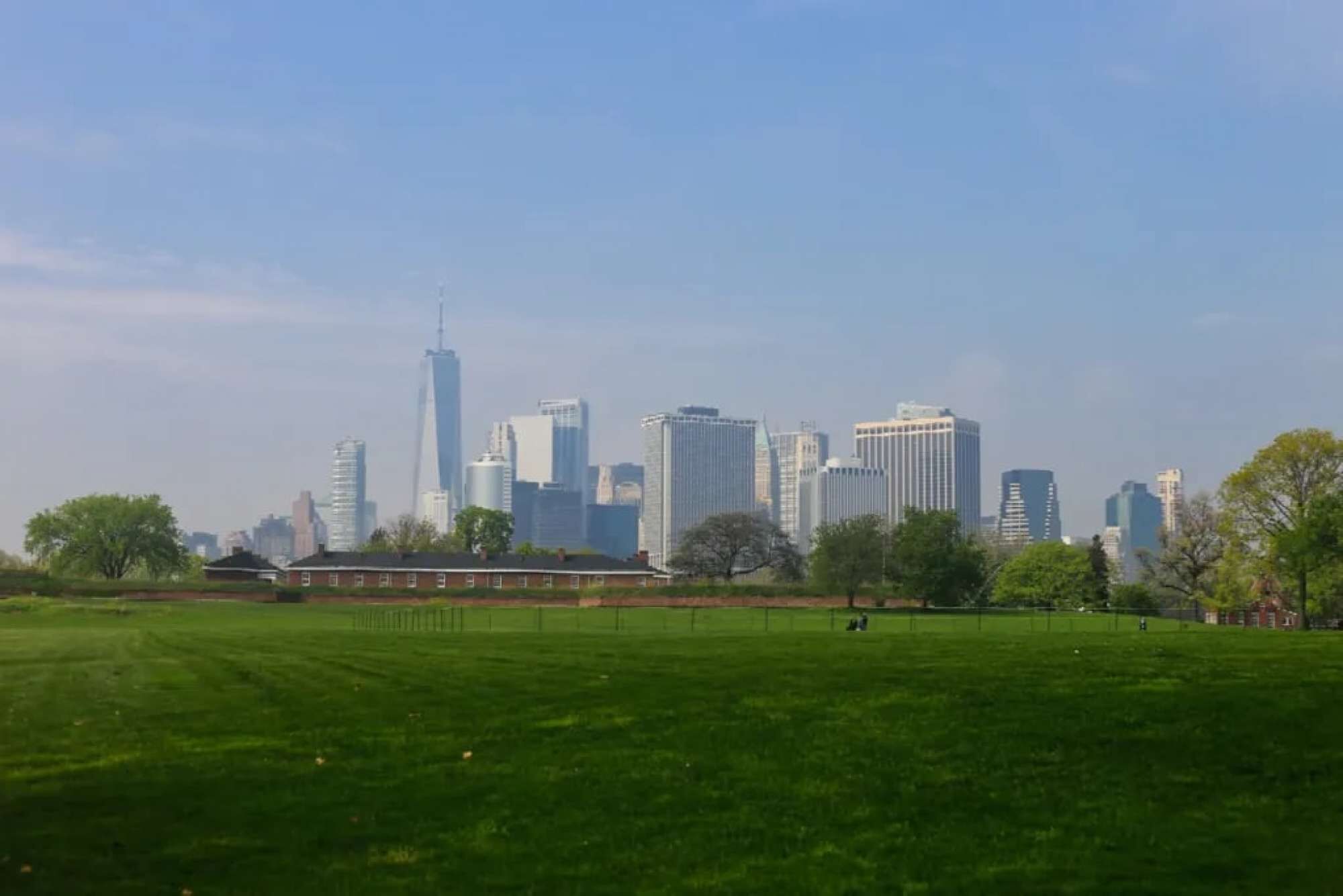 A city skyline with modern buildings and a large green park in the foreground.