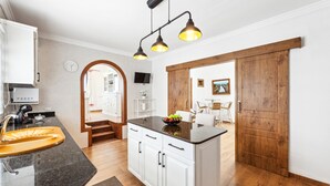 A kitchen with white cabinets, a black countertop, and a wooden door. - Villa doña Isidora - VipVipVillas (Teguise)