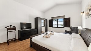 A bedroom with a bed, a TV, a dresser, a chair, and a window. - Villa doña Isidora - VipVipVillas (Teguise)
