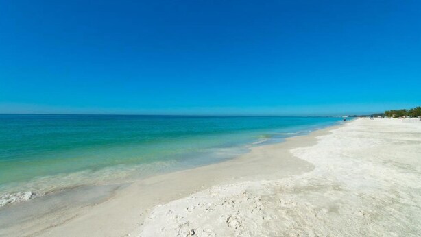 A beach with clear turquoise water and white sand.