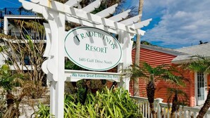 A sign for Tradewind Resort with a white pergola structure, located at 1603 Gulf Drive North.