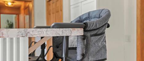 A dining area with a marble countertop and a grey upholstered chair with a headrest.
