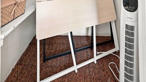 Espacio pequeño y cerrado con piso de madera, un equipo de aire acondicionado blanco y una mesa con superficie blanca.