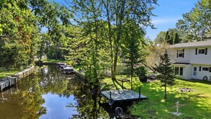 Un río tranquilo con un muelle, rodeado de exuberante vegetación y una casa.