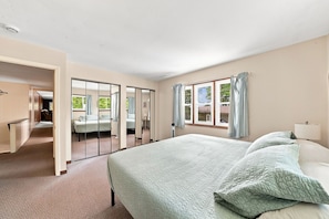 A hotel room with a large bed, a wardrobe, a desk, and a window with curtains.