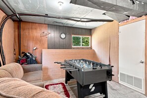 Une pièce avec une table de baby-foot, une horloge et une fenêtre.
