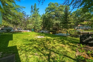 A well-maintained backyard with a grassy lawn, a wooden deck, and a small pond.