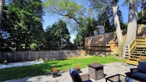 A backyard with a wooden deck, outdoor furniture, and a gravel patio.