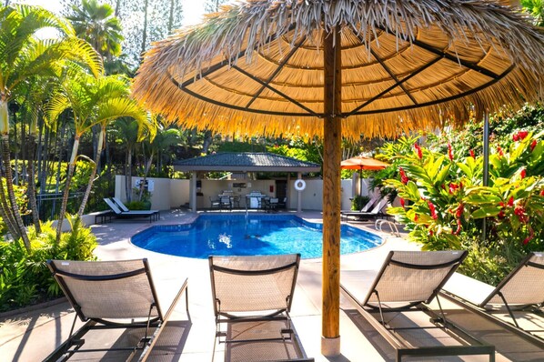A pool area with lounge chairs, a thatched umbrella, and tropical plants. - Kapalua Golf Villas Collection by KBM - 2 Units in same building (14p6/14v3) (Kapalua)