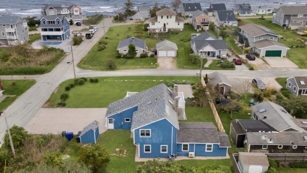 Un quartier résidentiel avec des maisons, une route et une vue sur l’océan.