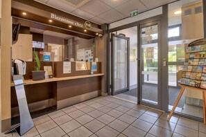 A reception area with a counter, a coffee machine, and a display of brochures. - B&B HOTEL Carcassonne Rocadest La Cité (Carcassonne)