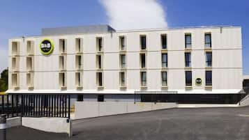 Ein modernes Gebäude mit einer flachen Fassade und zahlreichen Fenstern, mit B&B Logo.