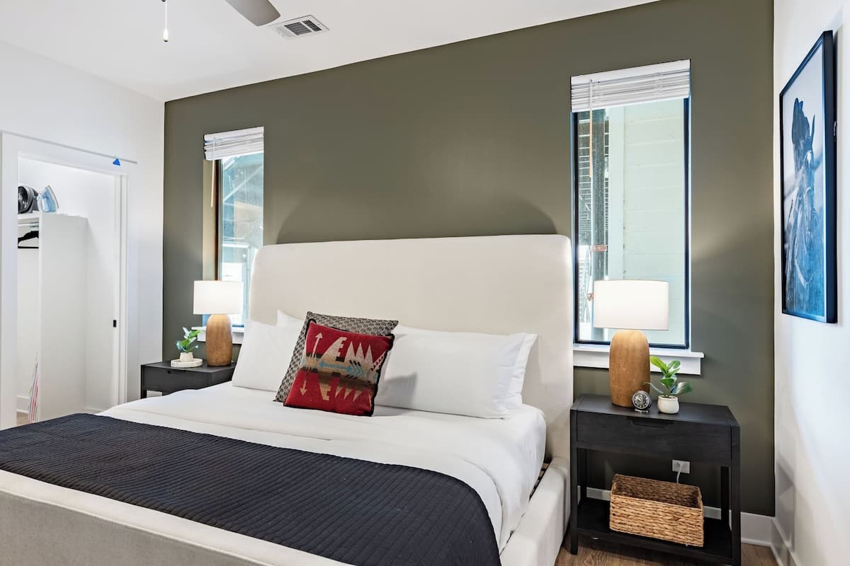 Una habitación de hotel moderna con cama, mesitas de noche, ventana y puerta.