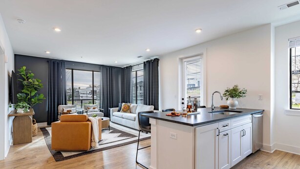 A modern apartment with a kitchen island, a living area with a sofa and a coffee table, and a large window providing a view of the city. - The Heights by AvantStay (Nashville)