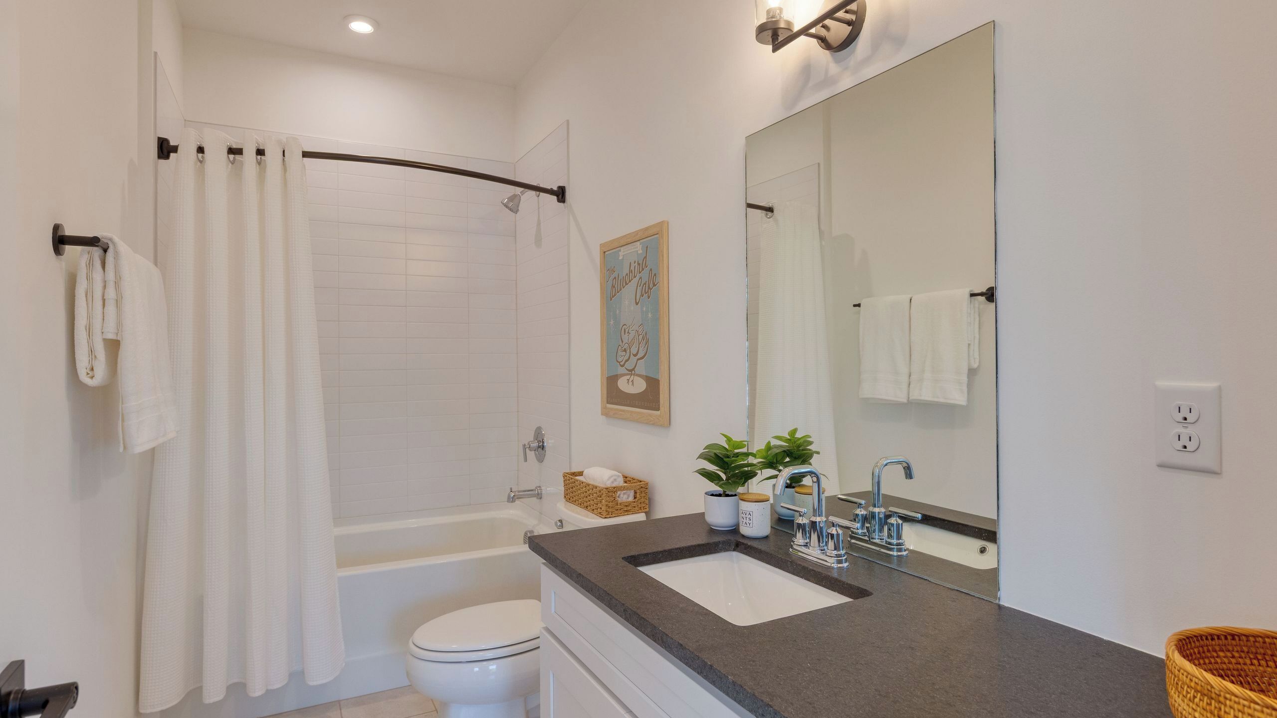 Une salle de bain équipée d’une douche, de toilettes, d’un lavabo et d’un grand miroir.
