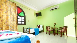 A hotel room with two beds, a small table with chairs, a TV, and a window with a curtain. - Riad Qodwa (Sidi Abdallah Ghiat)