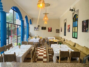 Un restaurant avec un sol à carreaux, des tables hautes et des chaises en osier.