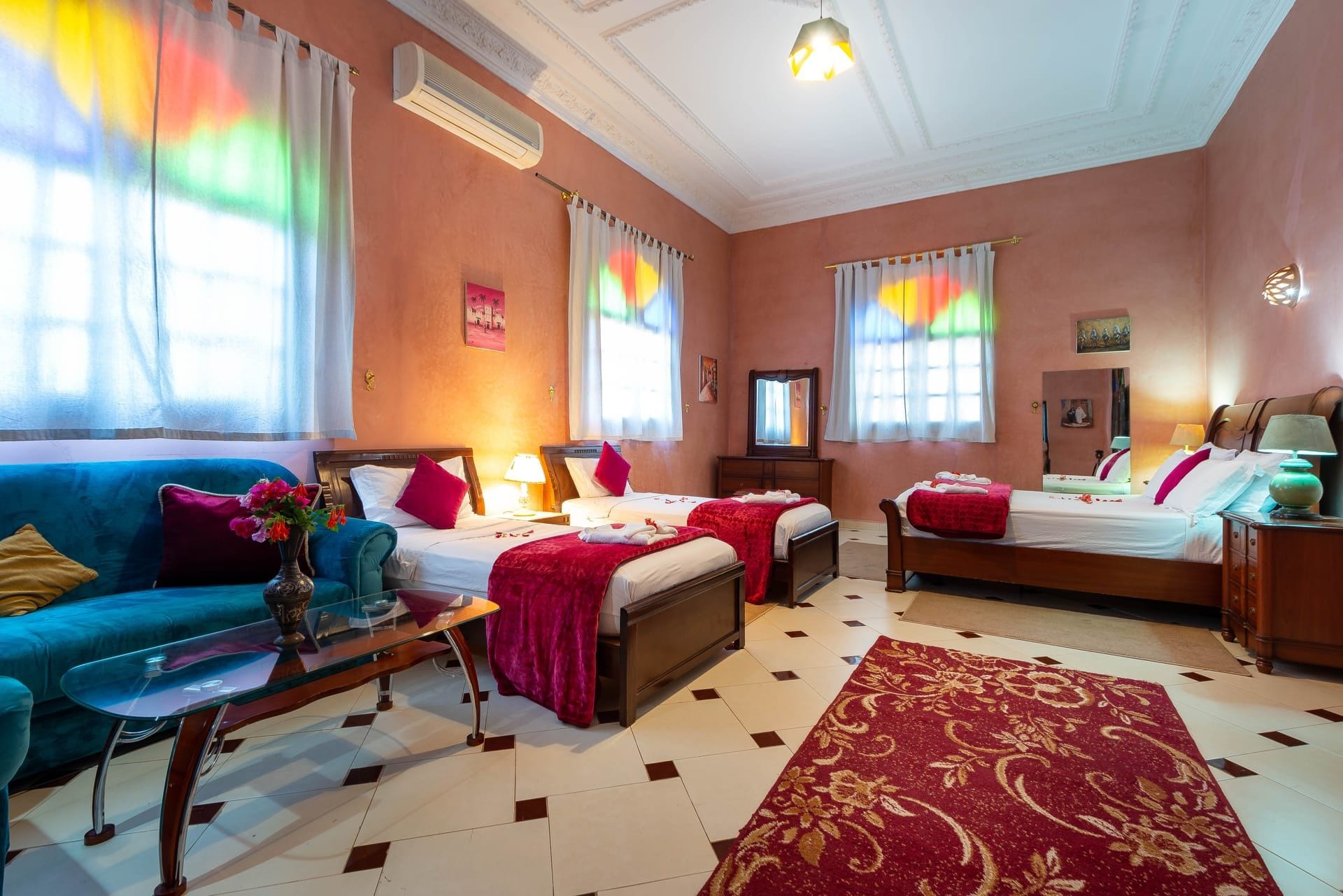 A hotel room with two beds, a sofa, a coffee table, and a large window with curtains.