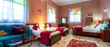 A hotel room with two beds, a sofa, a coffee table, and a large window with curtains.