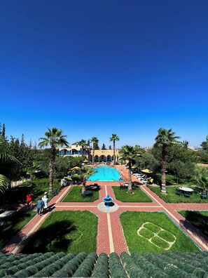 Une piscine entourée d’un ciel d’un bleu éclatant, de palmiers et d’un bâtiment en arrière-plan.