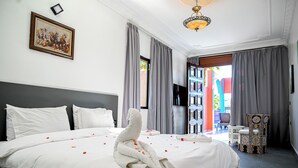 Ein Hotelzimmer mit einem großen Bett, einem Flachbildfernseher, einer Chandelüster und Blick ins Freie.