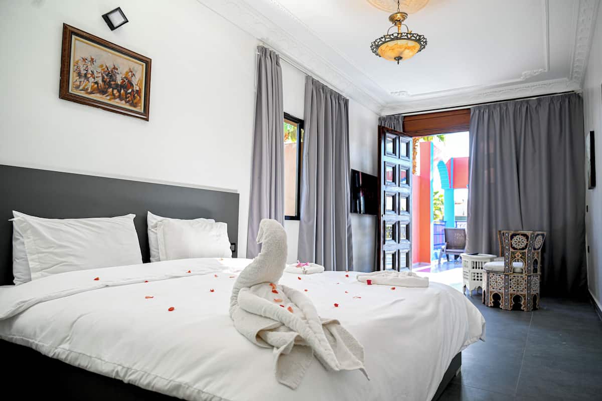 Quarto de hotel com cama grande, televisão de tela plana, lustre e vista para o exterior.