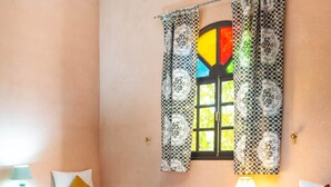 A hotel room with two beds, a red patterned rug, and a window with patterned curtains. - Riad Qodwa (Sidi Abdallah Ghiat)