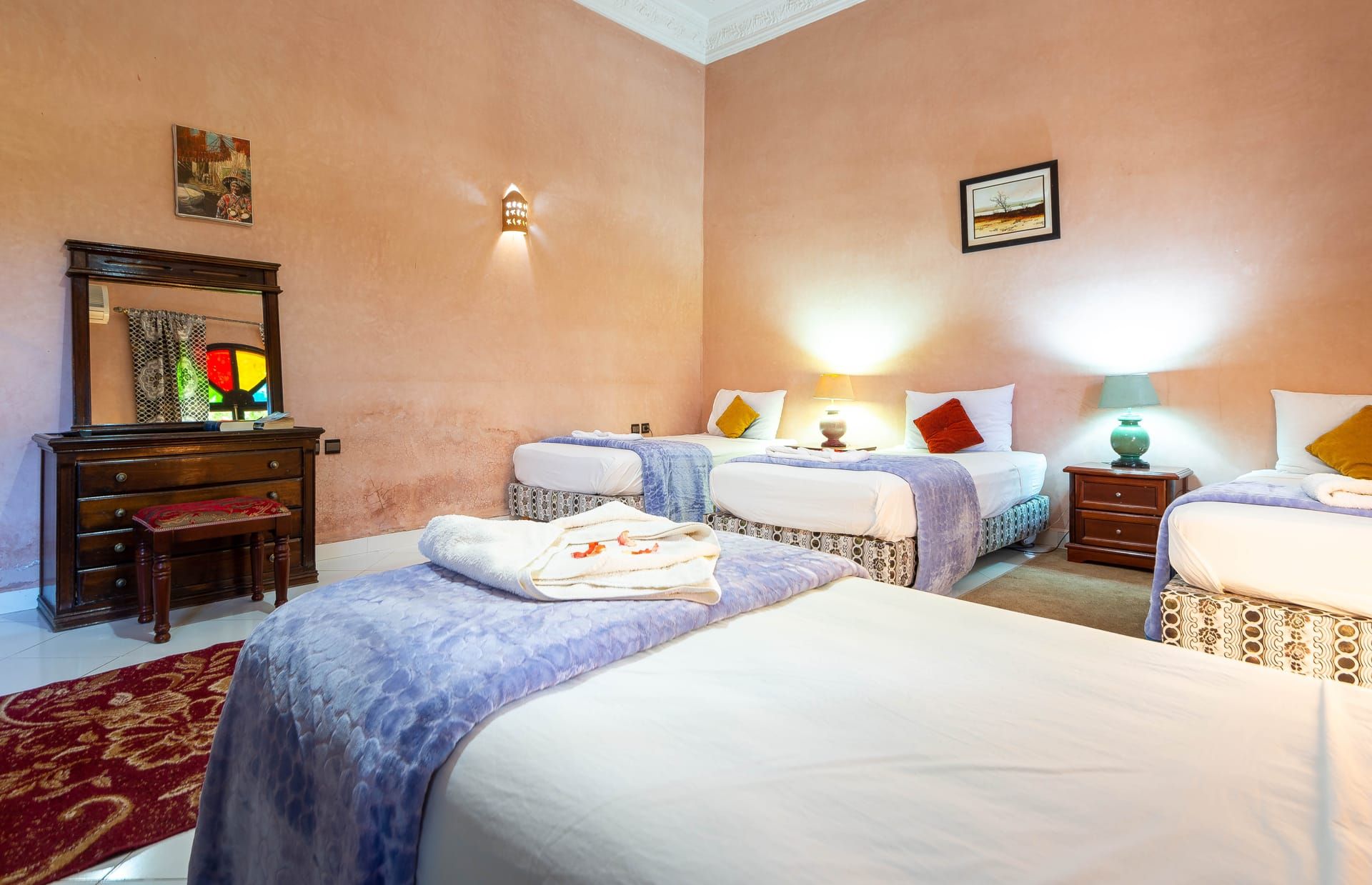 A hotel room with two beds, a dresser, a mirror, and a red carpet.