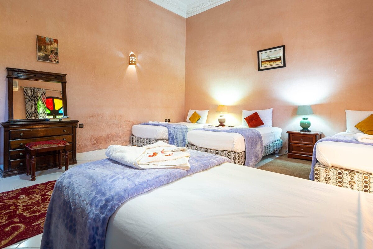 Une chambre d’hôtel avec deux lits, une commode, un miroir et une moquette rouge.
