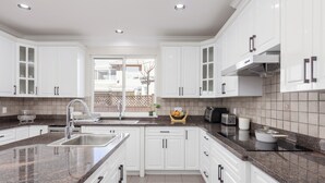 A modern kitchen with white cabinets, granite countertops, and a stainless steel sink.