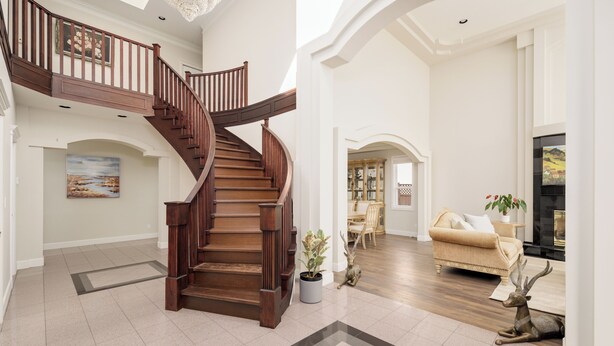 A spacious living area with a wooden staircase, a fireplace, and a chandelier.